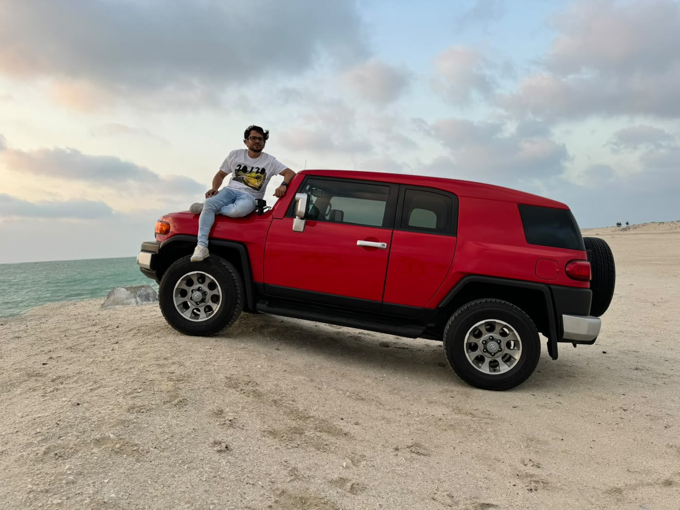 Shameem by the FJ Cruiser on the beach at dusk